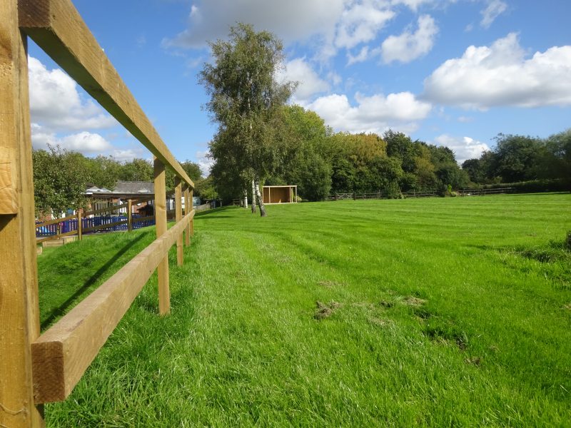 The school playing field with the school and pre-school buildings to the left.